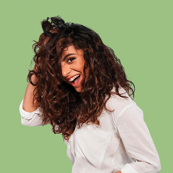 Woman holding her curly hair on a green background