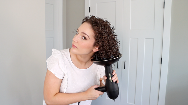 Woman styling her hair with a diffuser on a white background