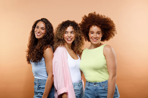 Three women with curly hair on an orange background