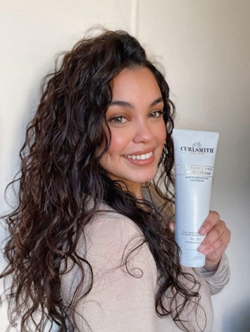 Woman with curly hair presenting a Curlsmith product