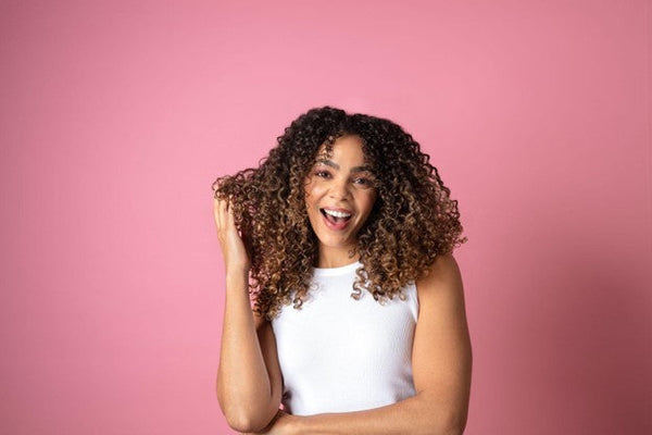 Woman with a culry ahir on a pink background