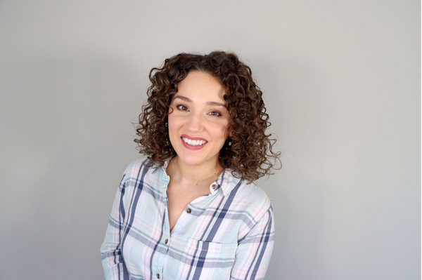 Woman with curly hair and a shir on a grey background