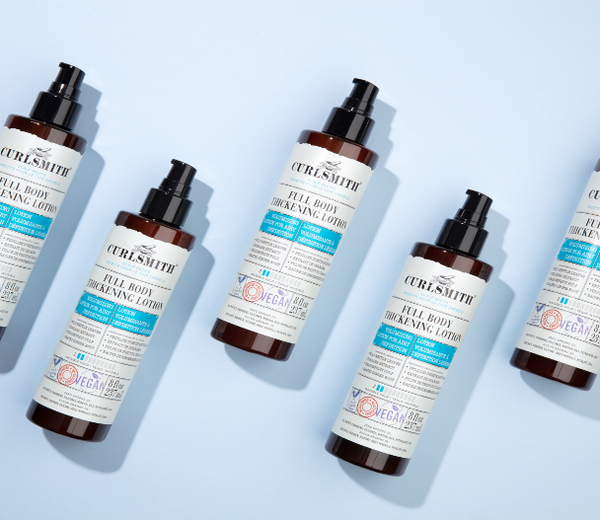 Curlsmith Full Body Thickening Lotions on a blue background