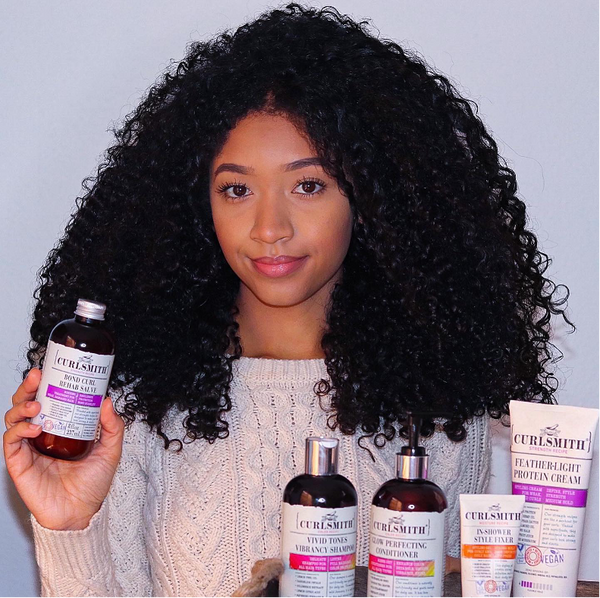 Woman with coily hair and Curlsmith products
