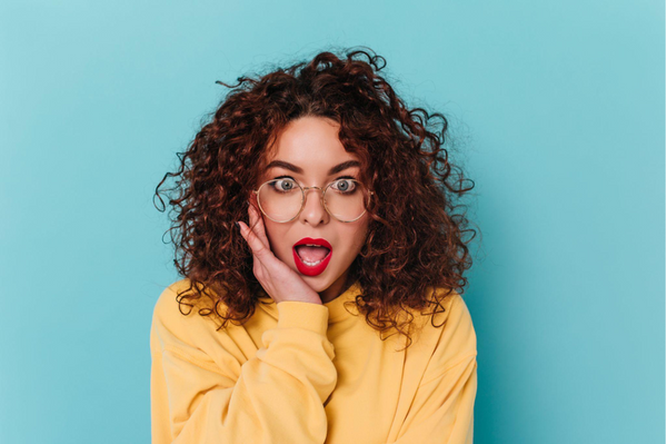Woman with curly hair and glasses on a blue background