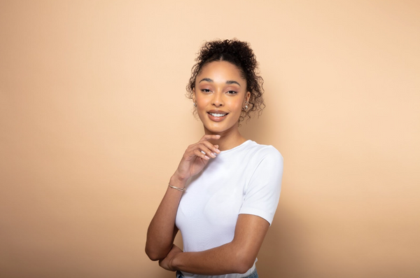 Woman with curly hair and a white T-shirt on an orange background