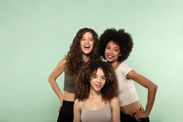 Three woman with curly and coily hairs on a green background
