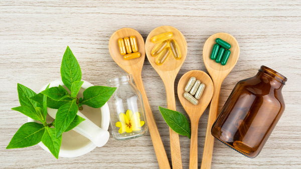 Four spoons with supplements and a bottle and a plant