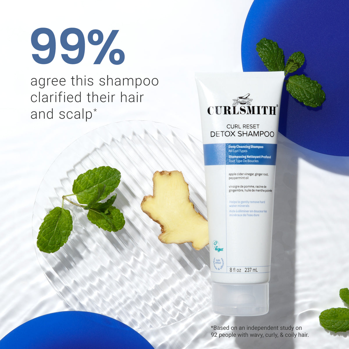 Curlsmith Curl Reset Detox Shampoo tube with ginger root and mint leaves on a white background