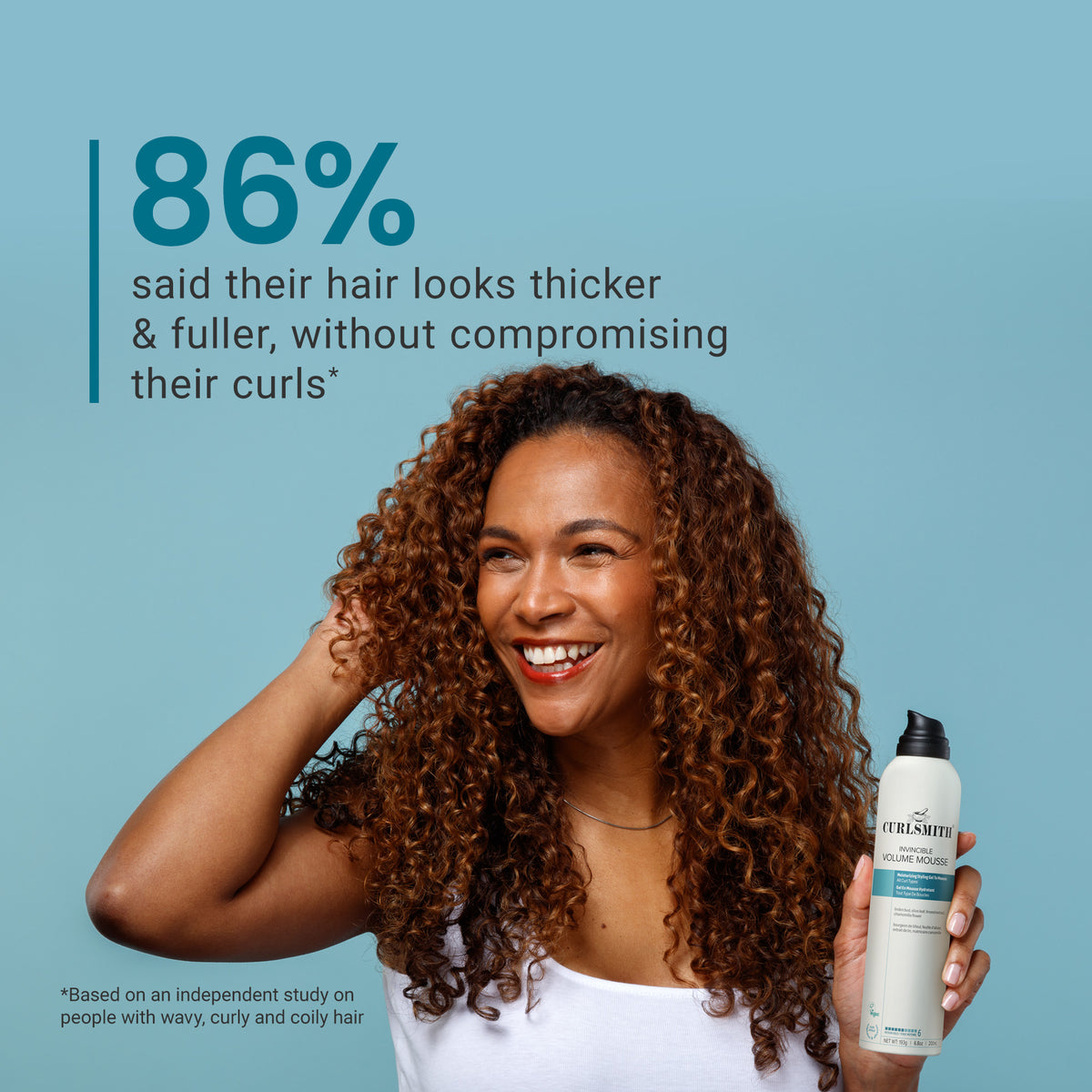 Woman with curly hair holding a bottle of Curlsmith product against a blue background